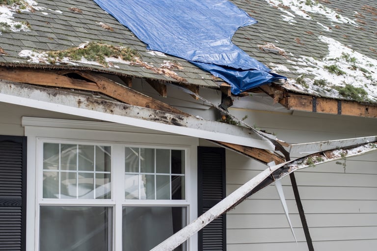 Residential house with storm damage, tarp placed on the damaged rooftop area as a temporary measure before proper repairs