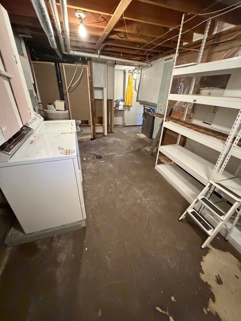 Restored basement with clean concrete floor, appliances, and shelving after sewer backup cleanup