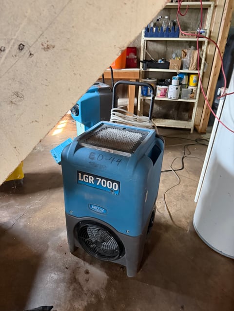 Blue LGR 7000 industrial dehumidifier in a workshop with shelving and equipment in background
